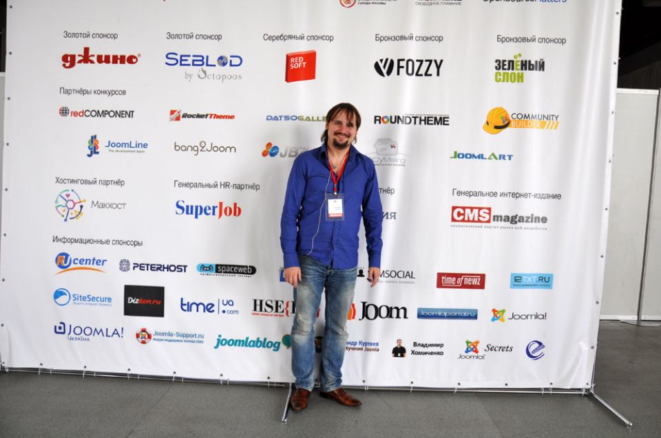 Дмитрий на фоне стенда Joomladay Russia 2014. Здесь есть и мы